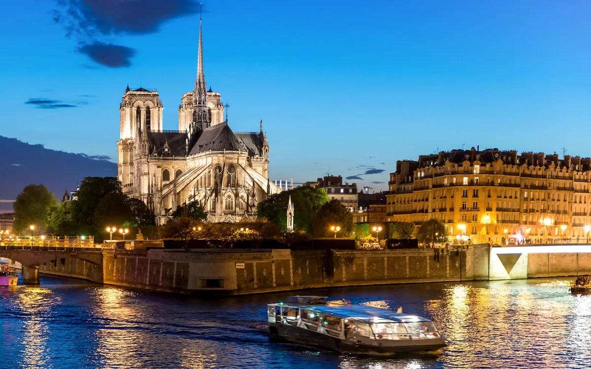 Boat passing illuminated Notre Dame at night