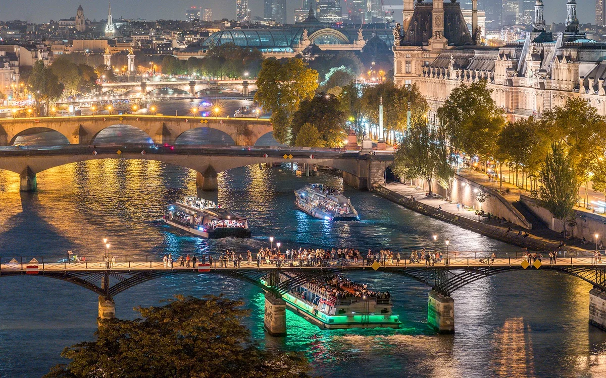 Illuminated sightseeing boat and Paris riverfront at night
