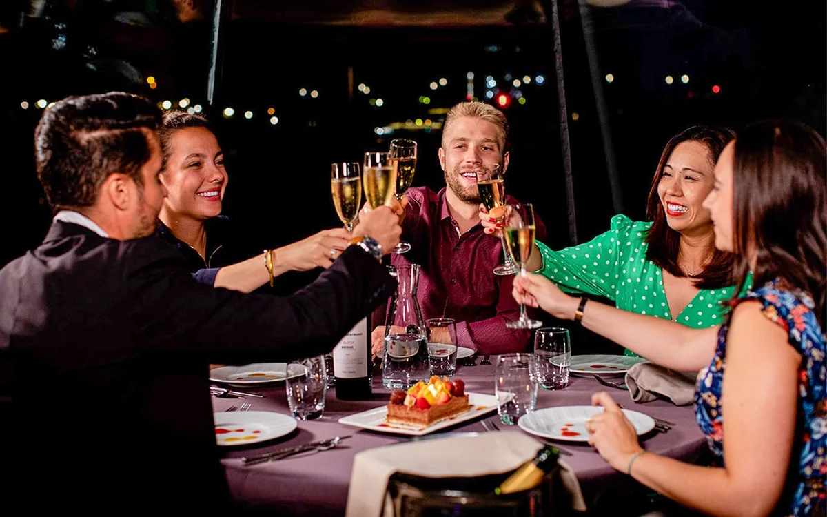 Guests sharing a meal aboard a Bateaux Parisiens dinner cruise